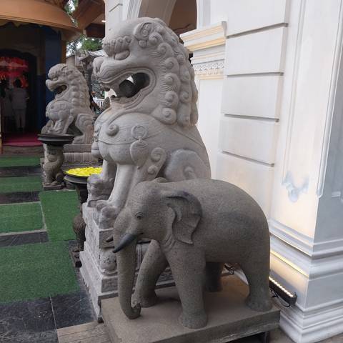       Stone elephant and lion statues outside a building.
  