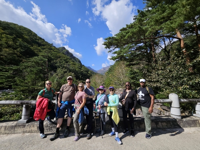 A group of people posing on a bridge in a natural park setting.