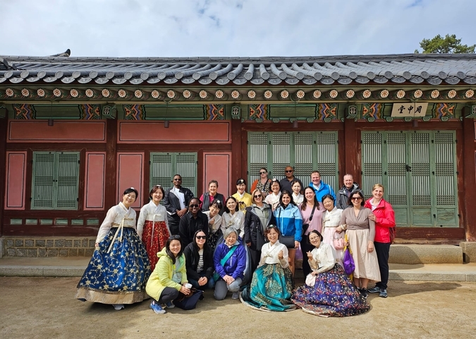 A large group of tourists posing in front of a traditional Korean building.