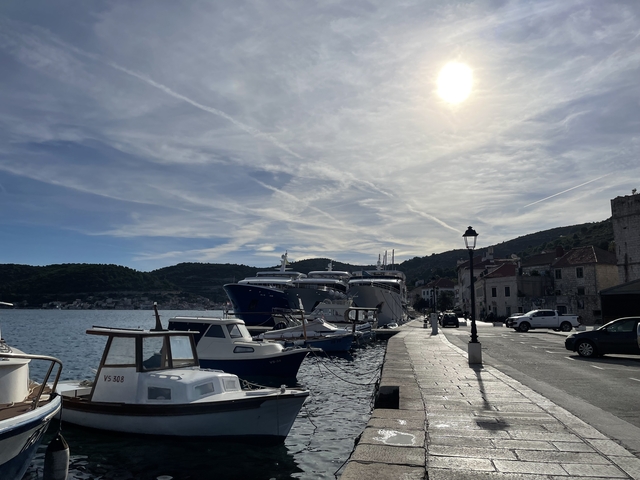 Several boats docked at a pier under a bright sunlit sky.