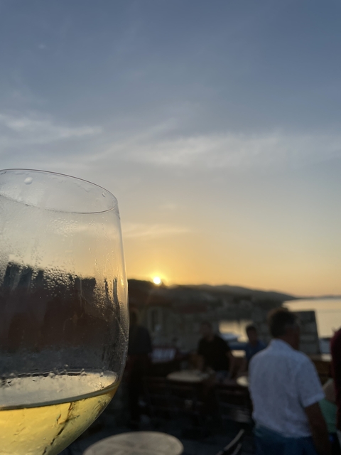 A wine glass with a sunset over the sea in the background.