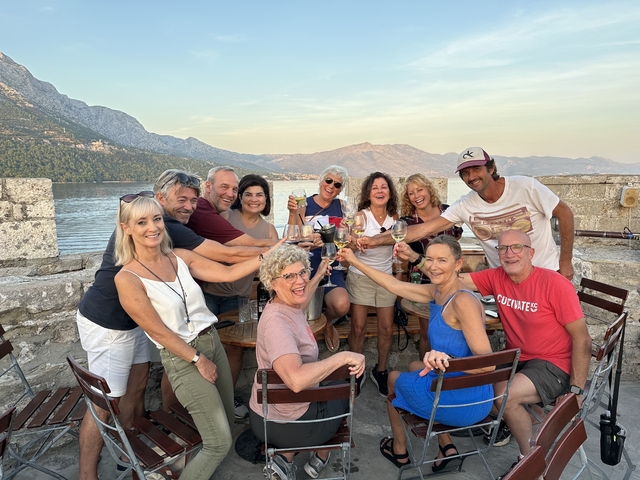       A group of people celebrating with drinks at a seaside restaurant.
  