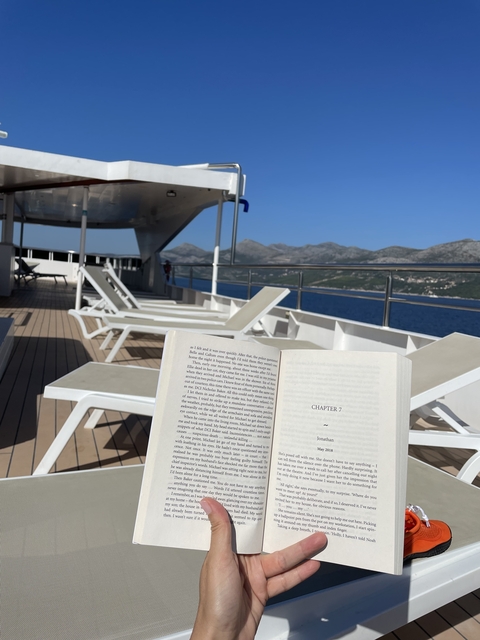       Open book on a deck overlooking the sea with lounge chairs.
  