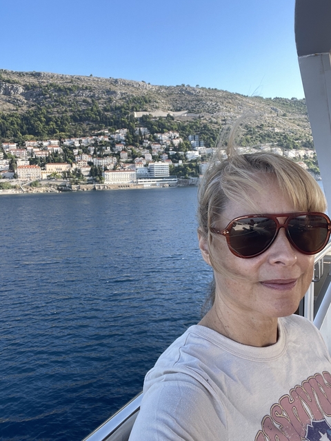       Close-up of a woman with coastal cityscape in the background.
  