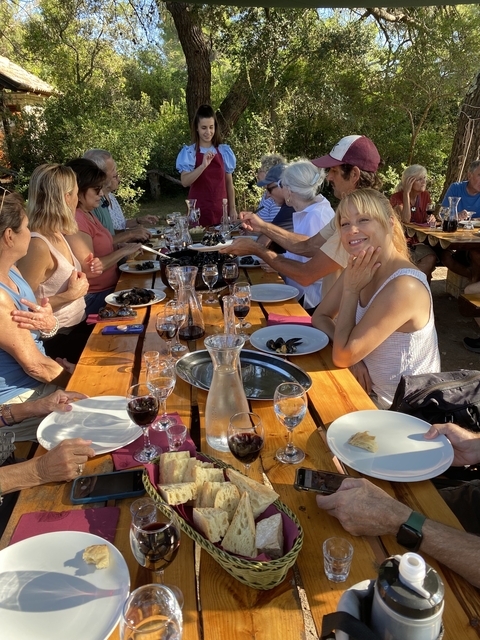       People enjoying a meal outdoors with drinks on the table.
  