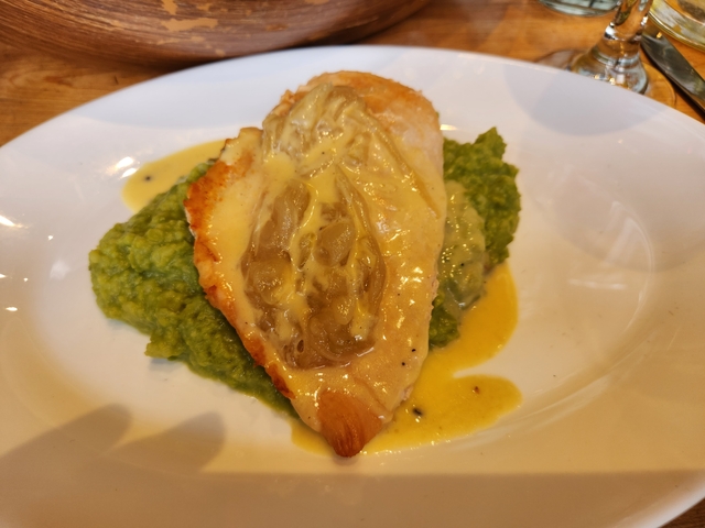 Gourmet dish consisting of roasted chicken with sauce and pea mash.