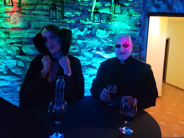 Two people in costumes sitting at a table with drinks.