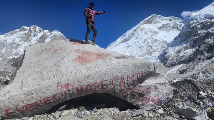 Person standing on a rock marked Everest Base Camp.