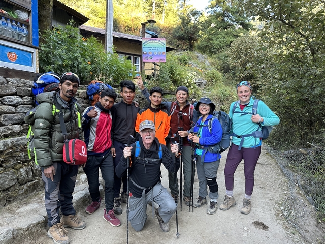 Group of trekkers posing by a building.