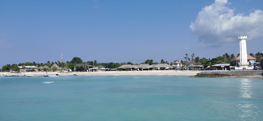       Beachfront view with huts and turquoise water.
  