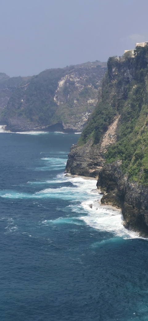 Cliffside view with waves crashing against rocks.