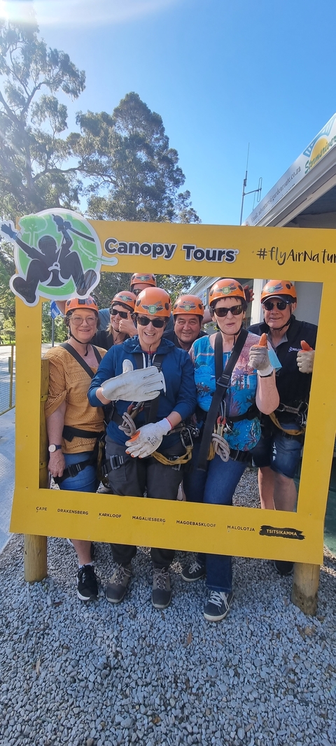 Group ready for a zip-lining adventure wearing safety gear.