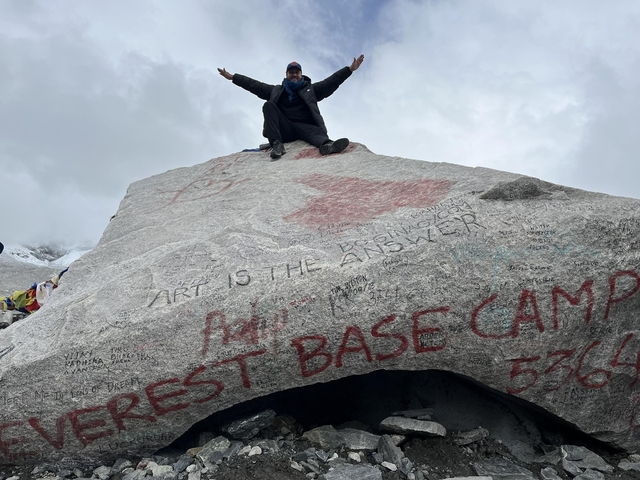 Person sitting on the Everest Base Camp rock.