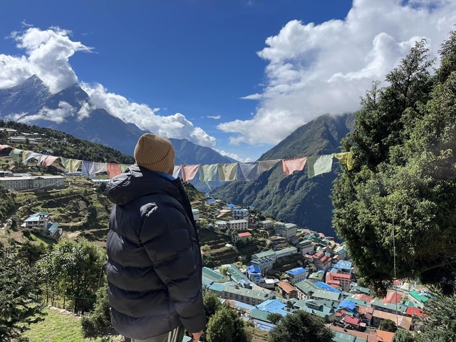 Person looking over Namche Bazar with mountains.