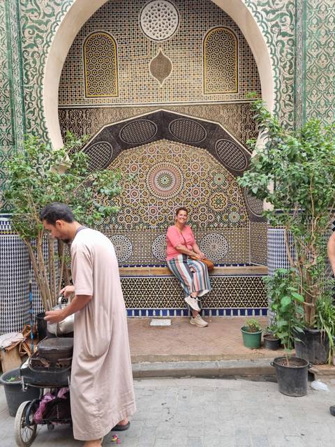 Person sitting in front of a decorative mosaic wall.