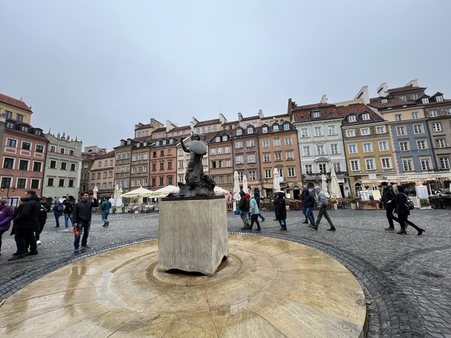 Colorful square with statue and people walking around.
