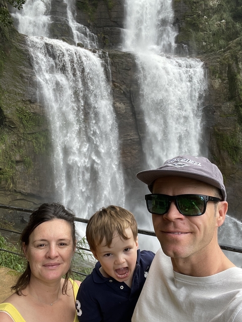       Family posing in front of a waterfall.
  