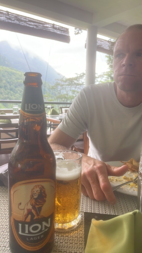       Person drinking a beer with a view in the background.
  