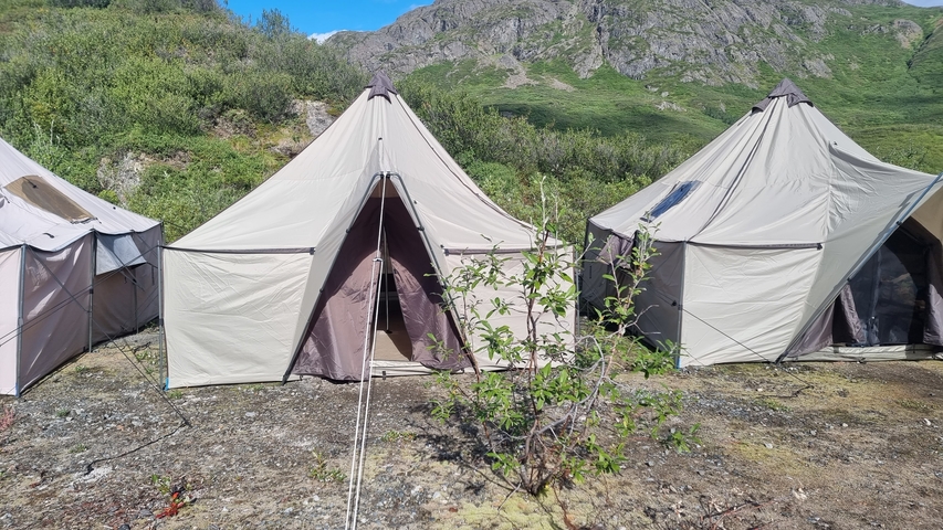       Row of tents set up in a mountainous area.
  