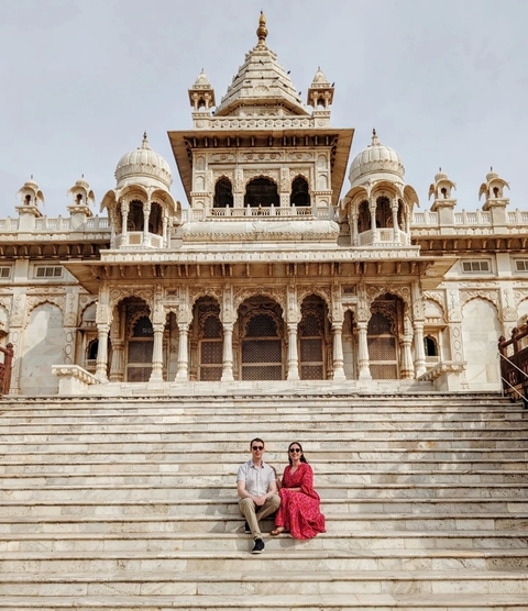 People sitting on the steps of a grand, ornate building.