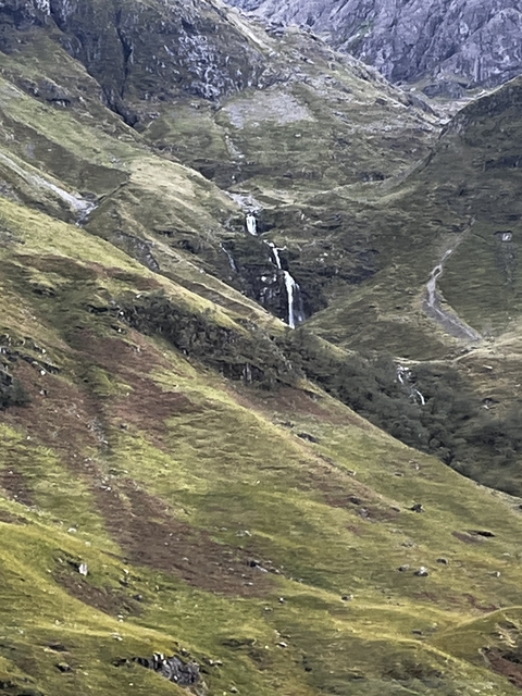       Scenic view of green hills with a waterfall in the distance.
  