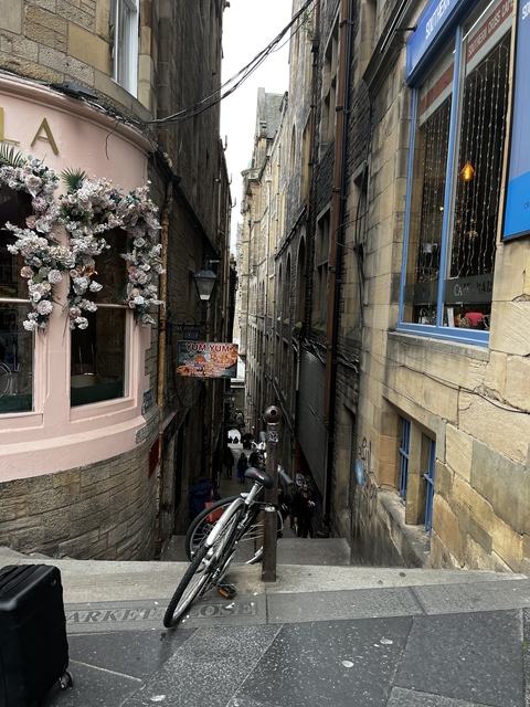 Narrow alleyway adorned with flowers and a small eatery.