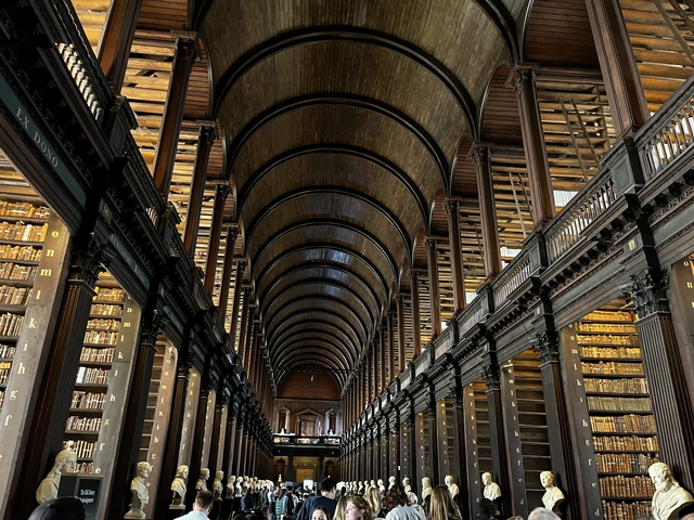       Long Room of a historic library with arched wooden ceilings and shelves.
  