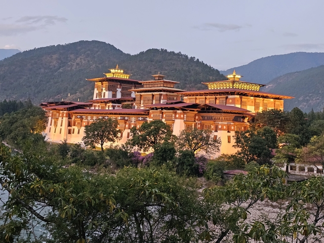       Illuminated traditional Bhutanese building at dusk.
  