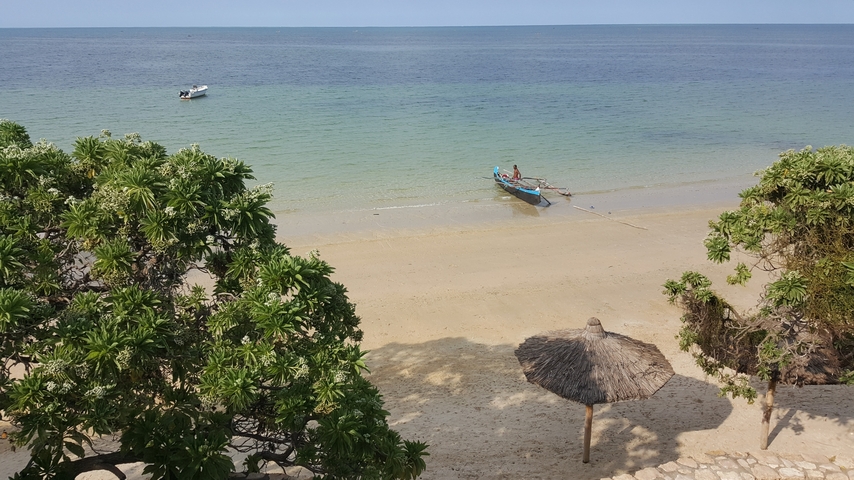       Beach with boats by the shore, ocean and clear sky in the background.
  