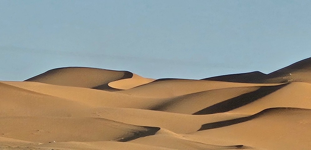 Sandy desert dunes under a clear blue sky.