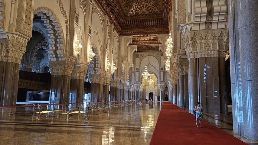 Elaborate interior of a grand mosque with chandeliers.