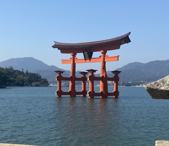       Traditional Japanese torii gate in water with mountains in the background.
  