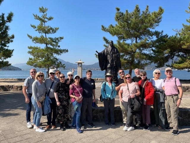       Group photo with a statue and trees near a waterfront.
  