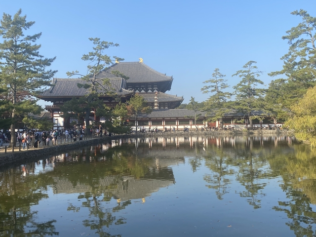       A picturesque temple with a large number of people reflecting over a pond.
  