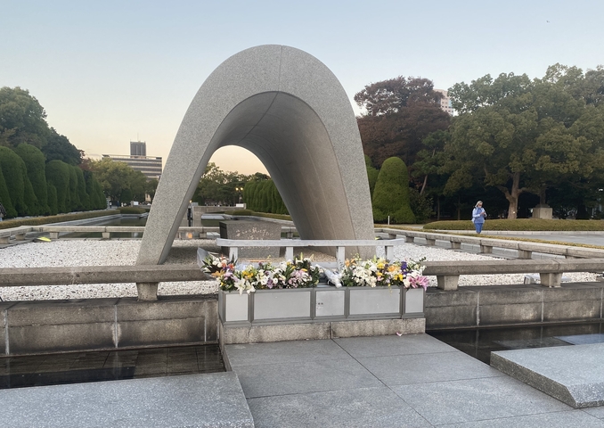 Peace Memorial with flowers in a serene park setting.