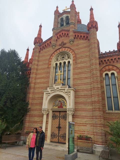 A red brick church with intricate details and a small group in front.