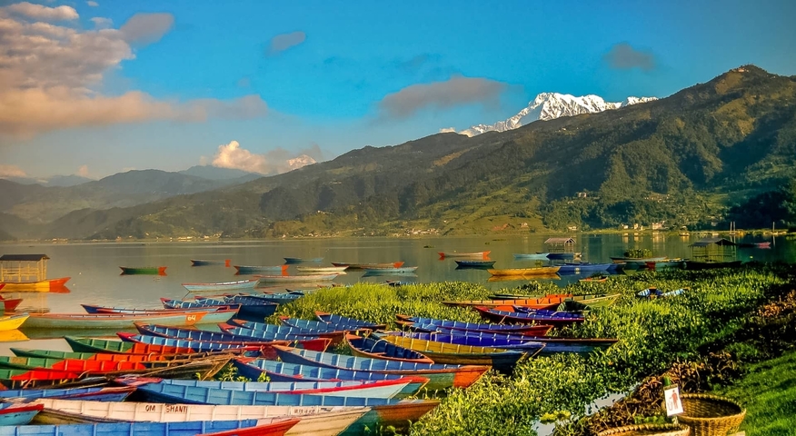 Colorful boats on a lake with mountains in the background.