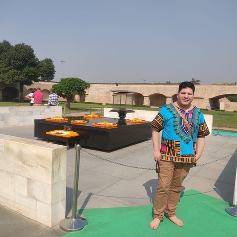 Man posing near a memorial with flower arrangements.