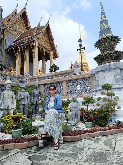 Tourist sitting among statues at a cultural site.