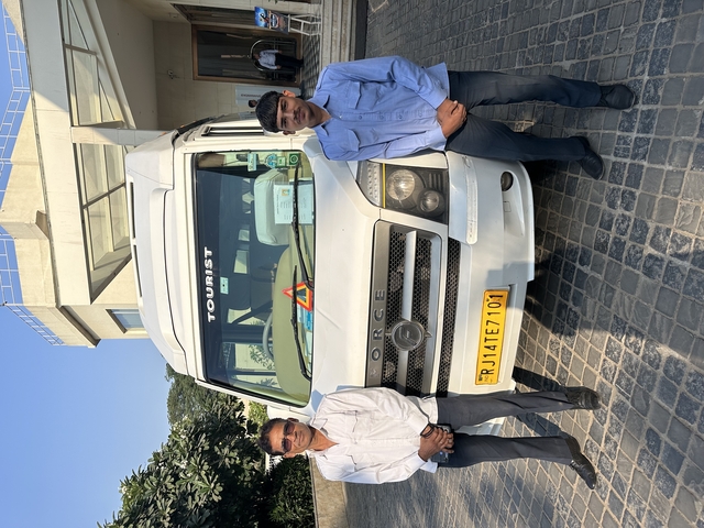 Two men standing next to a tour van in a parking lot.