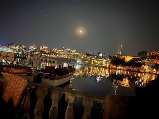 City skyline and reflection in water at night with a bright moon in the sky.
