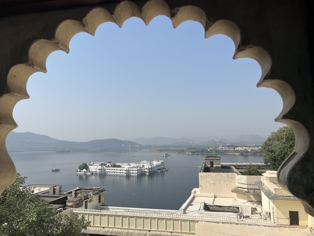 View through a decorative archway over a lake with a floating palace.
