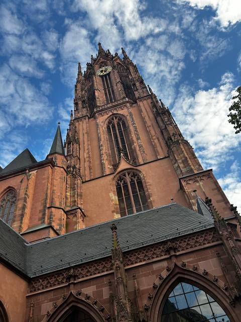 A close-up view of a tall gothic church tower against a blue sky.