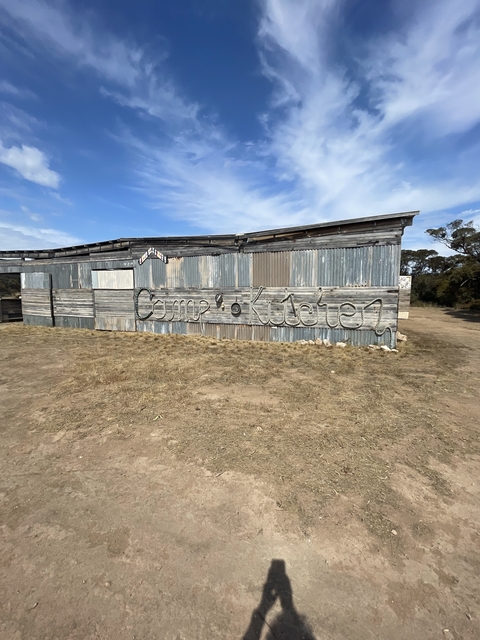       Rustic building with a corrugated metal facade and sign.
  