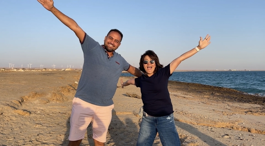 Two people posing by the sea