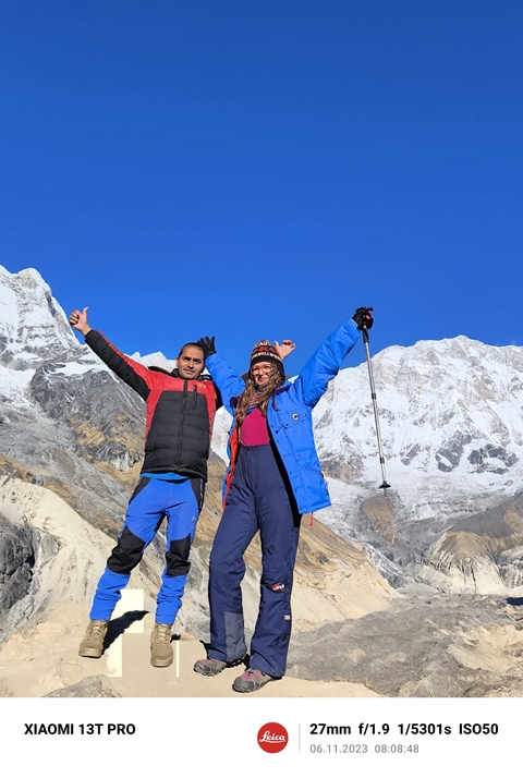 Two people posing with snowy mountains in the background