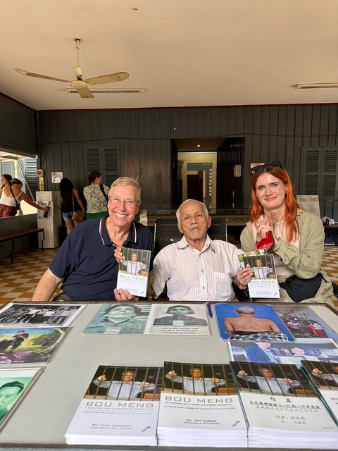       Three people holding books, indoors
  