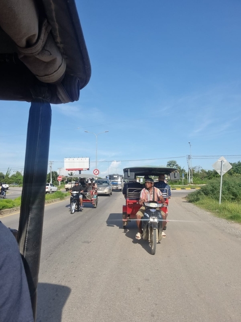       Tuk-tuks and motorcycles on a busy street.
  