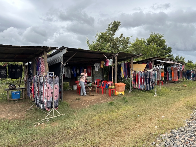       Market stalls with colorful clothing and items for sale.
  