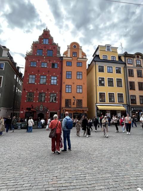       People walking through a historical city plaza.
  
